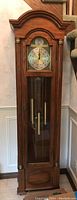 Full front view of wooden grandfather clock showing clock face, weights, and pendulum.
