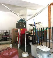 Metal rotary laundry hanger standing in a garage area, showing the full height and base.