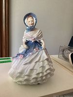 Front view of Royal Doulton "Alice" figurine with bonnet, shawl and ruffled layered dress
