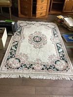 Full view of oriental rug showing central floral medallion and floral border with fringed edges.