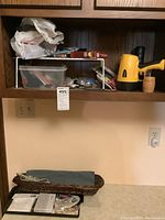 Shelf view showing some tools and a yellow and black handheld flashlight with a basket on lower shelf