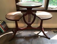 Full view of tiered accent table with lyre base and claw feet showing three tiers and wood finish.