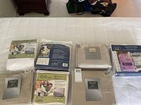 Photo showing packaged bed linens including sheets and pillow protectors in neutral tones on bed.