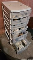 White plastic 6-drawer storage tower with translucent drawers, partially open showing contents