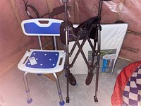 Photo showing the complete lot including the shower chair, stander/walker and posture cushion in a corner with pink insulation background.