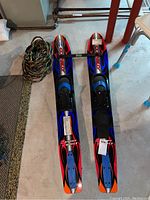 Pair of water skis with training bar and tow rope on concrete floor