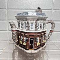 Front view of the teapot shaped like an East End pub with detailed brickwork and painted windows and flowers.