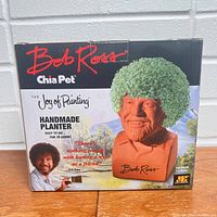 Front view of the Bob Ross Chia Pet box showing the product image, Bob Ross signature, and 'Handmade Planter' labeling