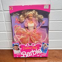 Front view of Costume Ball Barbie doll in original packaging wearing pink and orange lace ball gown with accessories visible.