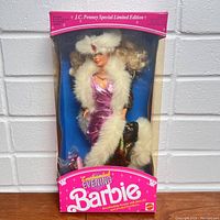 Front view of Enchanted Evening Barbie Doll in original pink box with clear plastic window, doll dressed in pink gown with white faux fur stole and matching hat, sitting inside the box.
