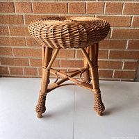 Photo of rattan stool showing woven round seat and supporting legs with cross braces