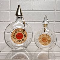 Front view of both Guerlain Shalimar perfume bottles showing labels and metal stoppers