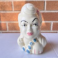 Front view of the vintage lady head vase showing facial features including painted eyes, lips, and decorative buttons