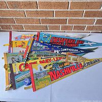 Vintage souvenir pennants arranged fan style, showing locations and colorful illustrations on fabric.