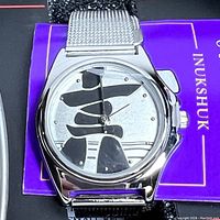 Close-up of the watch face showing the Inuit Inukshuk design and silver mesh strap.