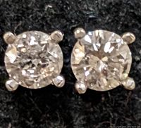 Close-up front view of diamond stud earrings on black background