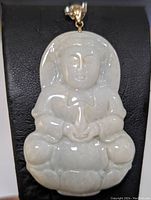 Front view of jadeite pendant carved as seated figure with 14K yellow gold bail.