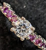 Close-up of round brilliant center stone and pink accent stones on one side