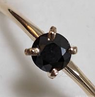 Close-up top view of round black diamond and prong setting