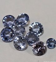 Top view of ten loose round faceted tanzanite gemstones in various sizes and blue-violet shades.