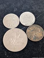 Four mixed coins on black background showing obverse and reverse of silver and copper coins.