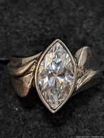 Close-up front view of sterling silver ring with marquise-cut cubic zirconia stone set in a bezel setting, showing detailed band design and facets of the stone.