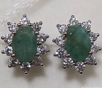 Top view close-up of the oval emerald and cubic zirconia stud earrings showing the floral arrangement around the emeralds.