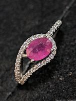 Close-up photo of the ring showing the oval ruby center stone surrounded by sparkling cubic zirconia stones on sterling silver band.