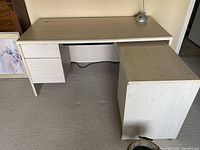 Light wood laminate L-shaped desk showing attached two drawer file on left and run-off on right side
