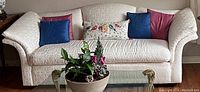 Large white fabric sofa with floral pattern upholstery and five accent pillows.