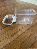 Photo of a clear rectangular Lucite container with open lid showing a clay insert embedded inside the lid for moisture retention.