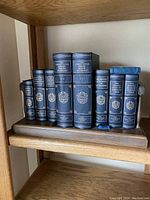 Shelf with eight older Oxford University Press reference books with blue hard covers, gilt titles and some cases visible on ends.