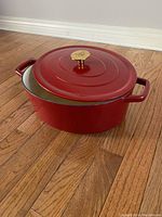 Red enamel cast iron Cookware pot with lid, 6-quart, on a wooden floor.