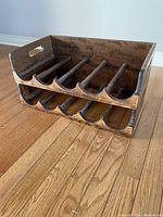 Photo shows dark stained wooden wine rack with two levels, each can be separated. Each level has curved bottle slots for storage.