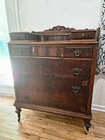Front view of antique chest showing ornate hardware and wear on wood finish