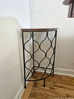 Side view of the semi-circular corner table with black metal frame and wooden top showing normal wear.