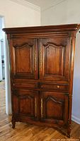 Full view of the large vintage wooden TV armoire with four panel doors and two drawers