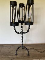 Full view of the 1950s folk-art chain-link electric candelabra lamp showing three cage-like lamp holders and chain-link base and stem.