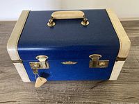 Exterior front view of the vintage Flite Dominion travel case showing blue body with white accents and gold locks and handle.