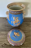 Front view of large blue porcelain lidded jar with detailed relief of Hercules on horse slaying lion, showing jar and separate lid.