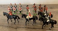 Group photo of 16 metal toy soldiers including mounted cavalry and infantry figures on a wooden surface.