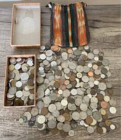 Top-down photo of the entire coin lot spread out on a wooden surface along with a small cardboard box and a colorful fabric pouch