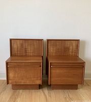 Front view of the pair of teak nightstands showing matching wood grain and drop-down front panels.