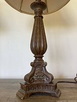 Close-up of carved wooden base of one lamp showing fluted design and decorative detailing.