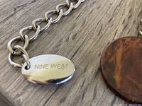 Close-up of metallic tag reading 'NINE WEST' on one of the belts