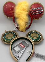 Photo showing two Disney Parks Marvel Mickey Mouse ear headbands: Captain Marvel with yellow mohawk and red ears with text, and Black Panther Wakanda Forever with gold and blue detail.
