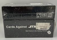 Two unopened boxed sets of Cards Against Star Wars with starry black packaging, shrink-wrapped with age and player info visible.