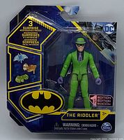 Front view of The Riddler first edition action figure in original sealed blister packaging, displaying figure seated and a visible three surprise accessory slots.