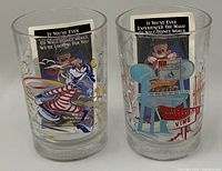 Two Disney-themed clear glasses with Typhoon Lagoon and Hollywood Studios designs, each containing a Walt Disney World vacation promotional brochure behind them.