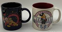 Two Disney mugs side by side, one black with colorful character design, the other white with maroon inner and Mickey Mouse tuxedo design